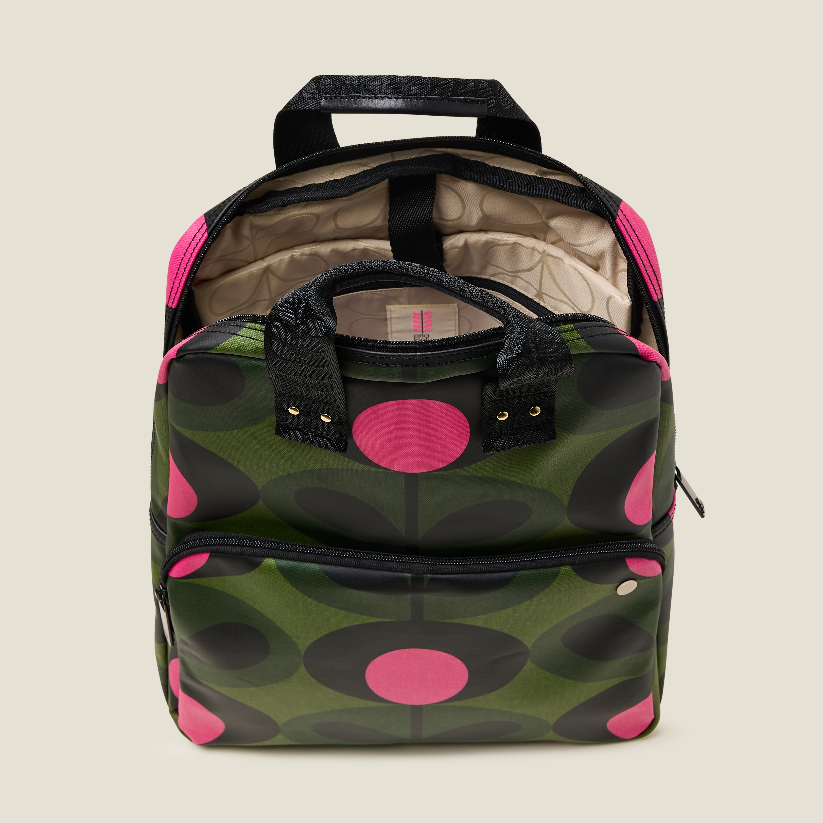 Inside view of  the Lotta Backpack in a green stem print with bright pink dots, featuring a padded laptop sleeve and branded beige lining.