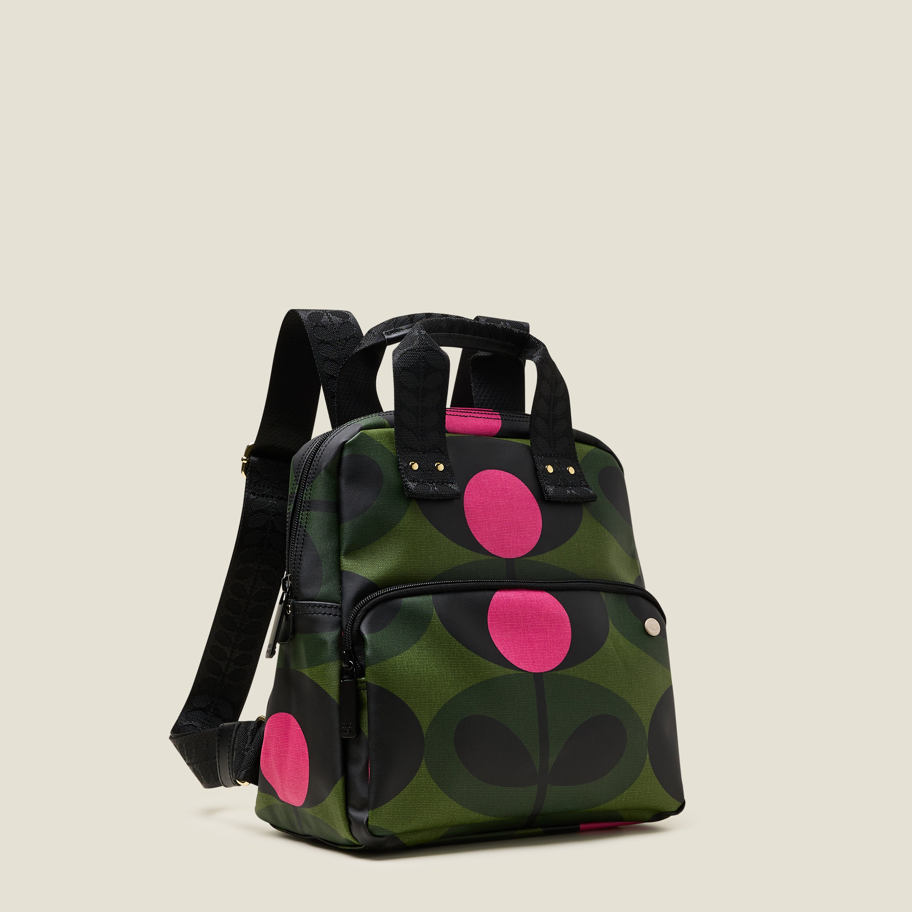 Side view of Mini Lotta Backpack in a green stem print with bright pink dots, featuring a zipped front pocket, branded grab handles and adjustable shoulder straps.