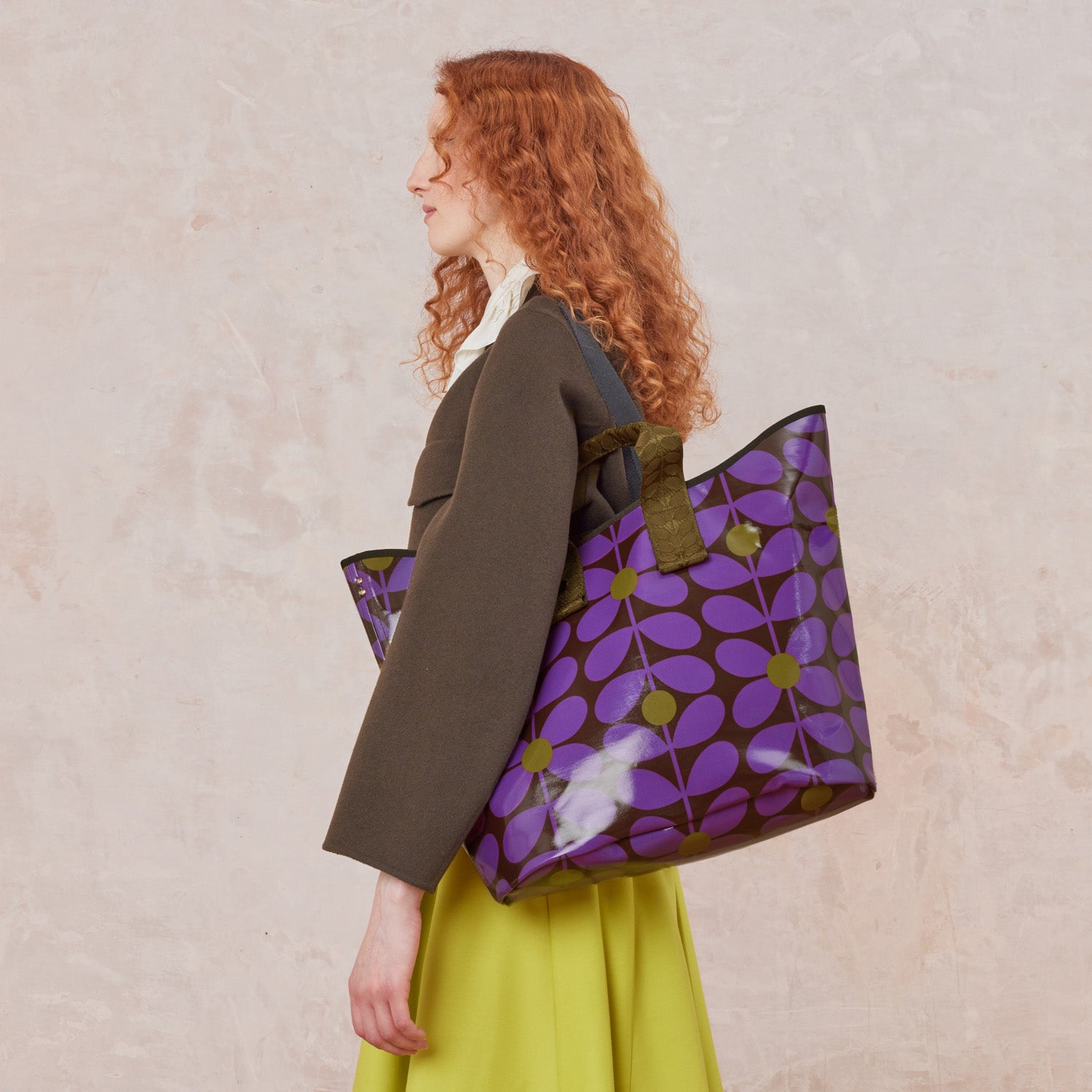 Woman holding a large retro inspired purple floral-patterned tote bag.