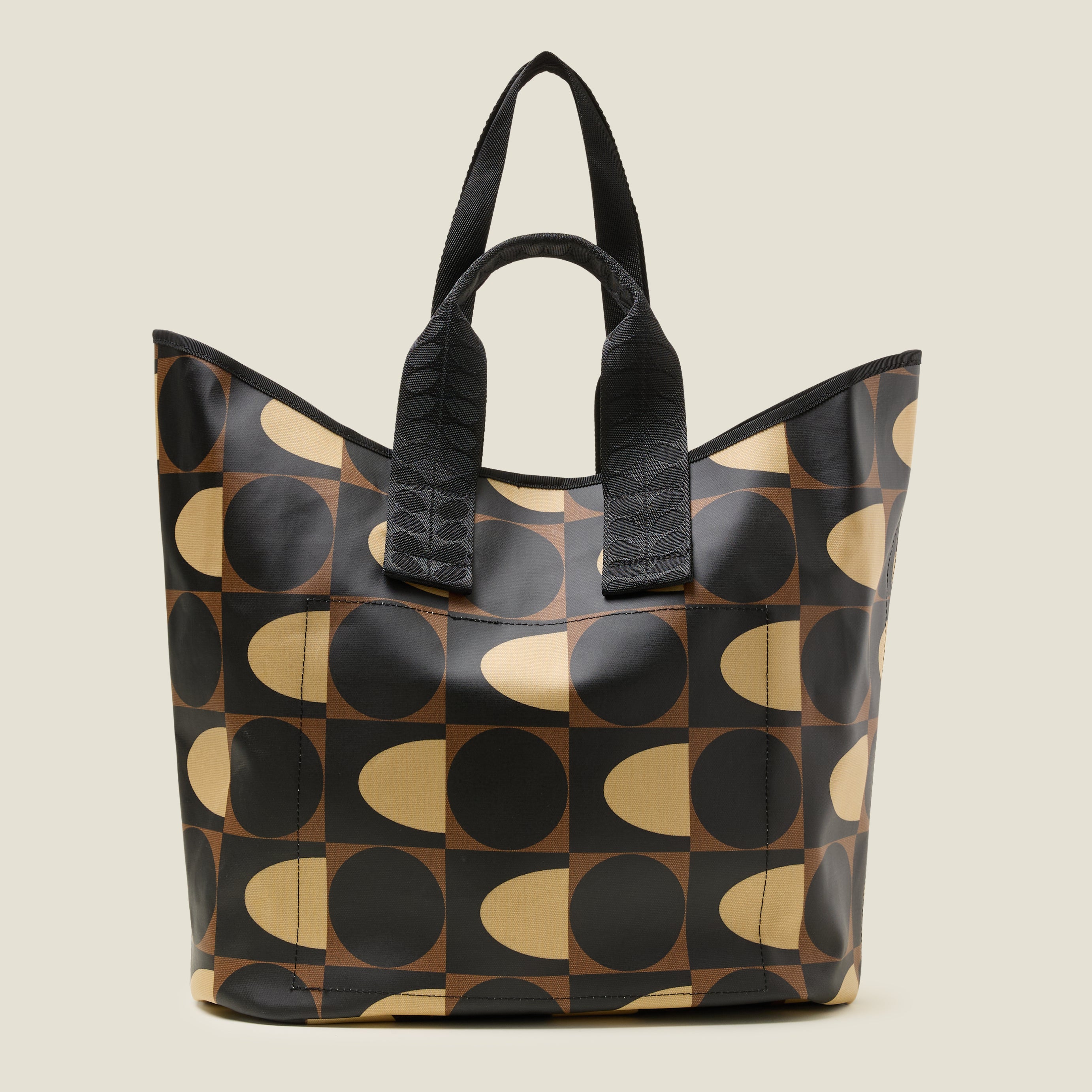 Side view of geometric patterned tote bag with black, brown and beige spot square printed design, with short grab handles and longer shoulder strap.
