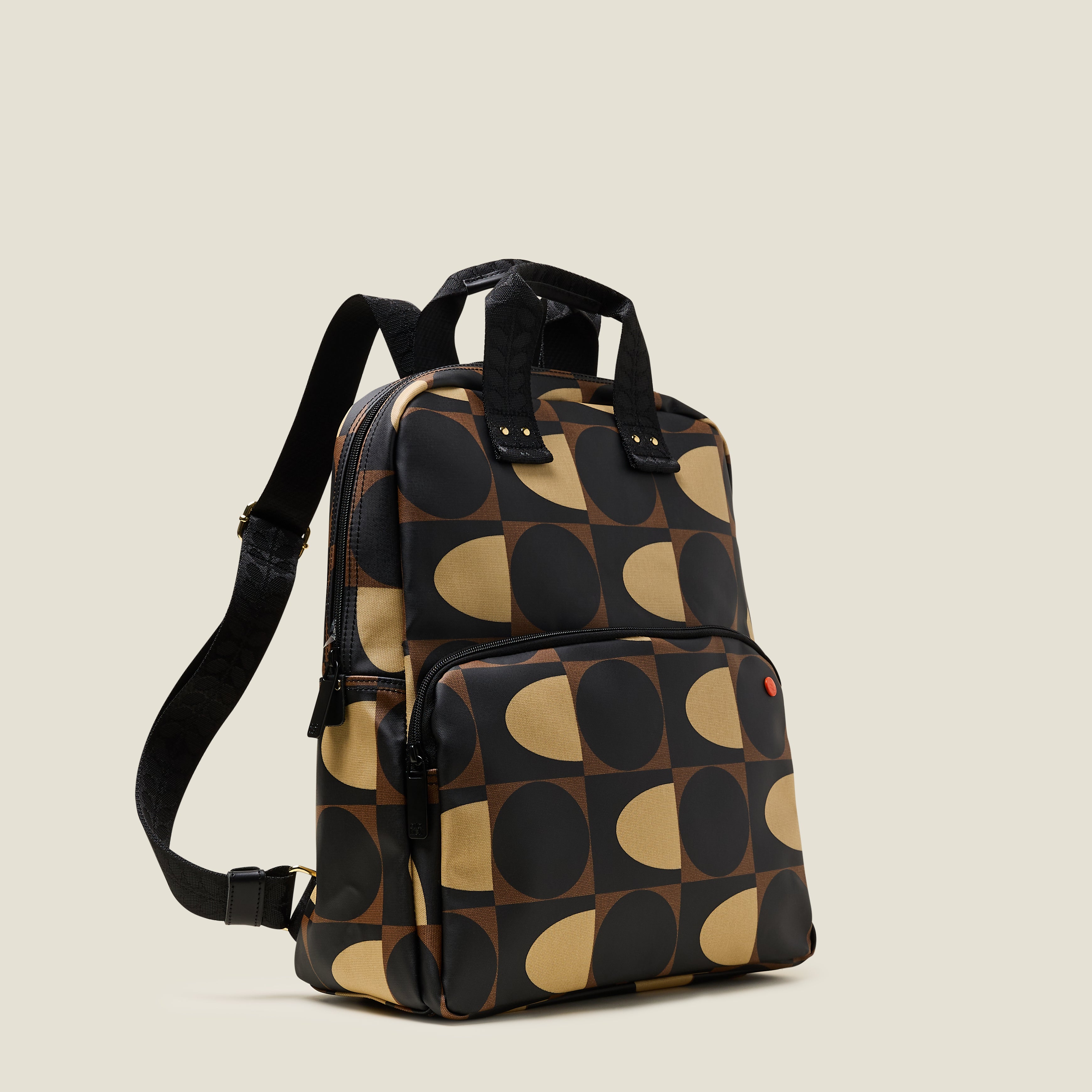 Side view of the Lotta Backpack in a brown and cream dot and squares print featuring a zipped front pocket, branded grab handles and adjustable shoulder straps.