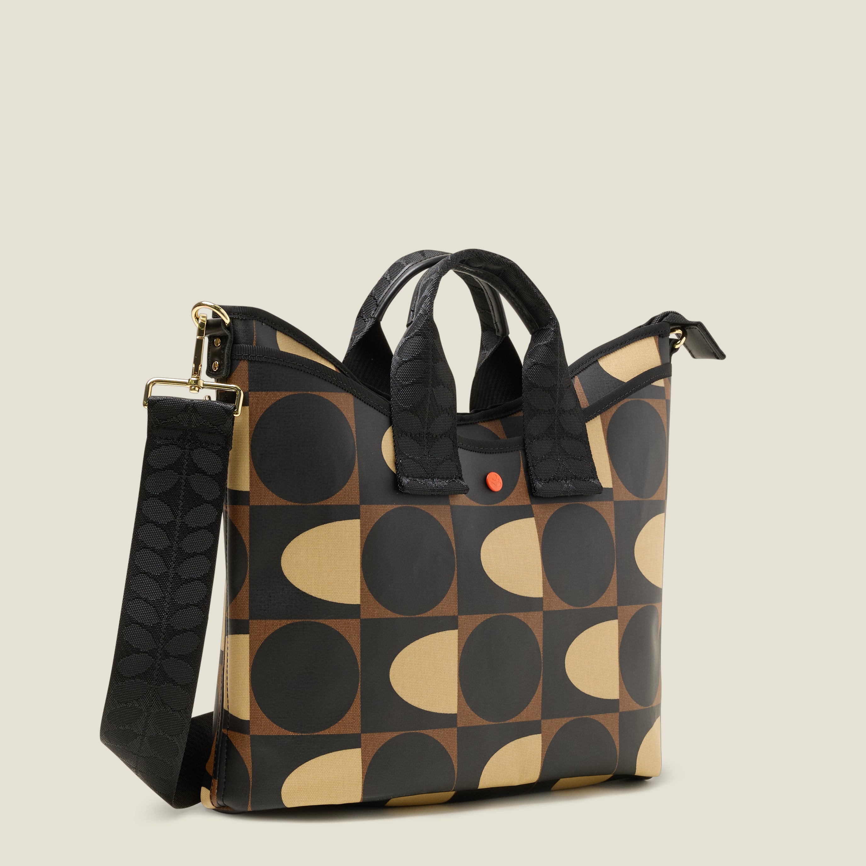 Side view of a patterned handbag, with slip pocket, branded handles with geometric mocha brown print design.