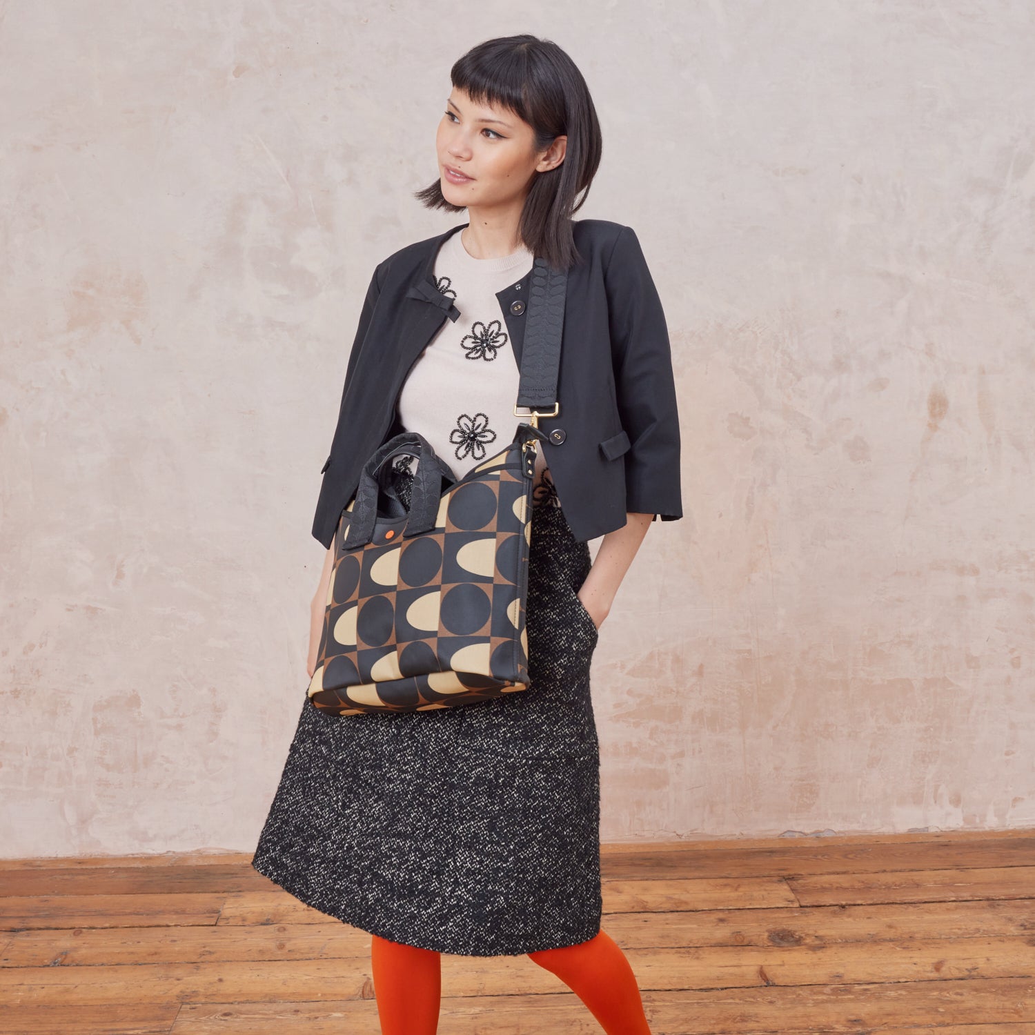 Woman wears the patterned Carrygrab Crossbody Bag in mocha brown.